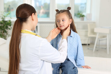 Doctor examining girl's throat in clinic during appointment