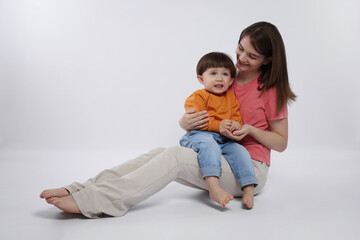 Happy mother with her cute little son on white background