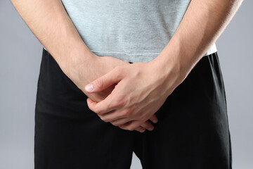 STD (sexually transmitted diseases). Man suffering from symptoms on grey background, closeup
