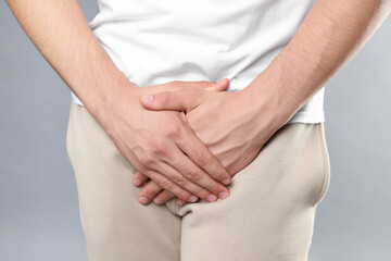 STD (sexually transmitted diseases). Man suffering from symptoms on grey background, closeup