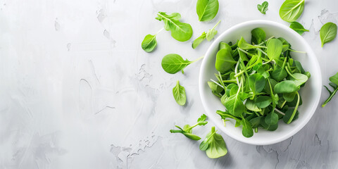A bowl of microgreens surrounded by scattered leaves on a light gray surface, highlighting their culinary appeal