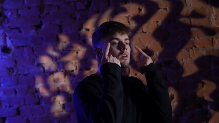 Young man in black clothes dancing hip hop against red brick wall