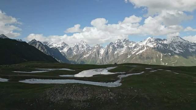 Aerial view of hiker at Koruldi lakes in Svaneti mountains, off-road SUV camper with roof top tent. Lone traveler explores nature, backpacking in scenic landscape. Adventure in remote location.