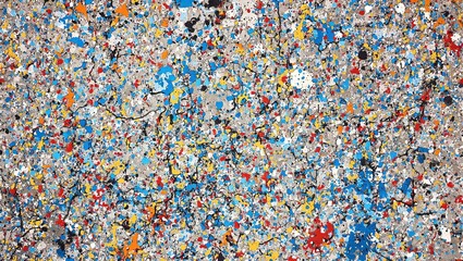 Vibrant paint splatters on concrete floor in blue red and yellow hues creating a chaotic and textured abstract design