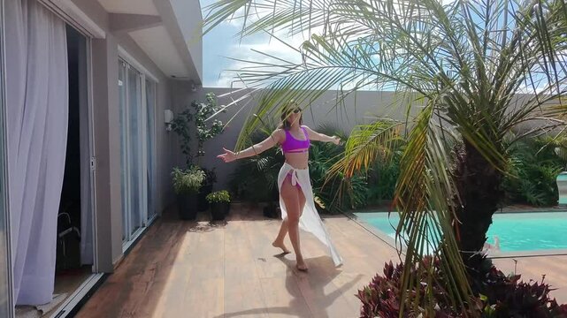 mulher influencer caminha por jardim com piscina no ver&atilde;o 