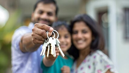 Homeowners. Happy young Indian family spouses standing outside holding car house flat apartment keys, celebrating new purchase buying real estate. Mortgage loan. New home. Mother, father and child