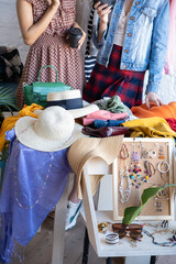 Young women at swap party. Choose casual clothes, shoes, hats, bags, jewellery. Idea of exchange your old wardrobe for new. Eco friendly cloth concept. Zero waste shopping, reduce and reuse, donation