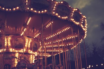 Illuminated carousel at dusk, showing lights and horses.