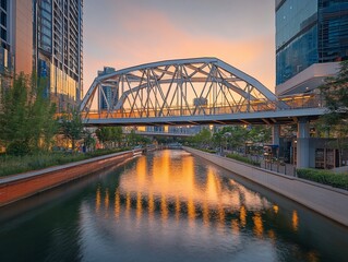 Fototapeta premium Modern bridge over calm canal at sunset, city buildings reflected in water.