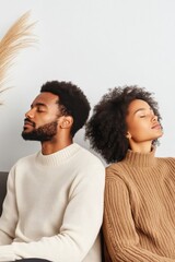 Obraz premium Couple sitting back-to-back on a sofa, reflecting on the emotional distance between them in a cozy living room setting