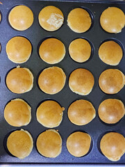 Hands preparing mini pancakes in a mold, they are turned over so that they are completely sewn for breakfast