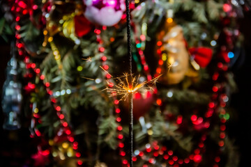 Beautiful sparklers burn against the backdrop of beautiful decorations on a Christmas tree during...