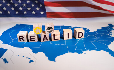 Wooden cubes composing the word rREAL ID on a map of the USA with an american flag. On May 7, 2025, U.S. travelers must be REAL ID compliant to board domestic flights and access certain federal