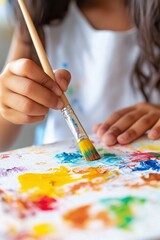 Naklejka premium Childs hands clutching a paintbrush, embracing creative expression in colorful artistry