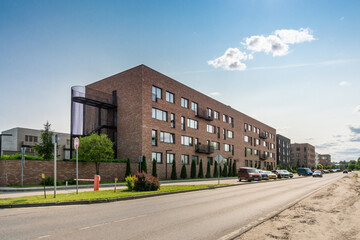 A residential street with modern buildings, parking for cars with a boom on the adjacent .territory, on a sunny summer day.