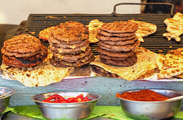 Burgers on grill with paprika and other condiments sold on a market stall