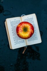 Fresh Apple with Water Droplets on Aged Book Pages in Moody Setting