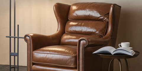 Obraz premium Cozy Leather Armchair with Book and Coffee. A comfortable brown leather armchair sits beside a small table with an open book and a steaming cup of coffee, creating an inviting and relaxing atmosphere.