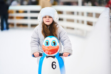 Young child enjoying ice skating with a playful penguin sled in winter © callisto