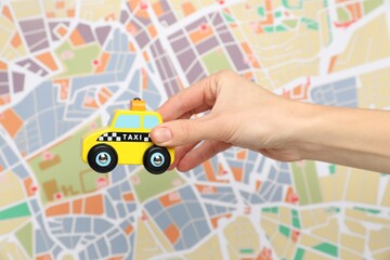 Woman with yellow taxi car against city map, closeup