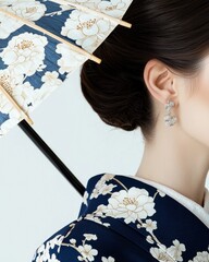 Fototapeta premium Elegant woman in blue and white geisha attire holding a parasol in minimalist studio setting