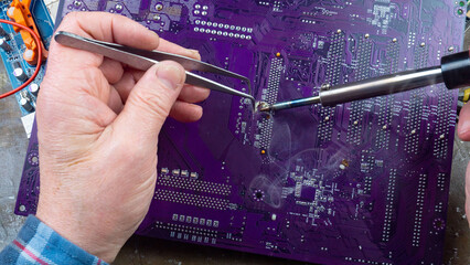 This photo shows the hands of an old electronics repairman diagnosing and repairing computer...