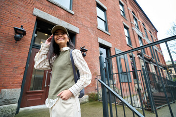 Happy cheerful teenage schoolgirl with school bag laughing in campus. Pretty smiling positive Asian teen girl college student with backpack standing in the city on street. Education abroad concept.