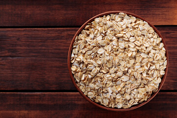 Clay Bowl Filled with Raw Oat Flakes On Brown Wooden Boards, Healthy Food Concept, Copy Space