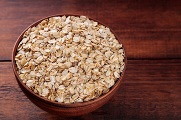 Clay Bowl Filled with Raw Oat Flakes On Brown Wooden Boards, Healthy Food Concept, Copy Space