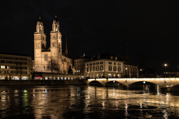 Fototapeta premium Nighttime View of Historic City Center with Illuminated Cathedral and Buildings in Zurich