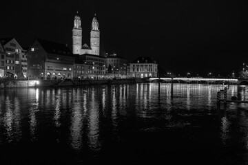 Fototapeta premium Nighttime View of Historic City Center with Illuminated Cathedral and Buildings in Zurich