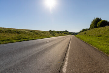 an empty straight paved road against a blue sky background