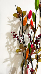 Colorful artificial floral arrangement with vibrant leaves and berries on a white background, ideal...