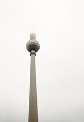 Berlin TV tower in dense fog, iconic Alexanderplatz landmark disappearing into mist. Foggy Fernsehturm in Berlin, Germany. Cloudy sky on background. Copy space
