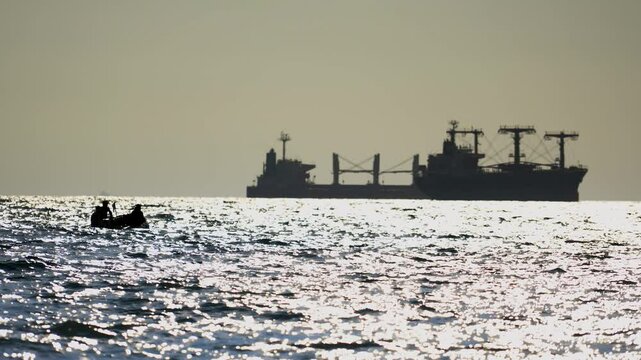 Modern pirates on an inflatable boat are about to attack a tanker or bulk carrier on the high seas. Silhouettes of sinister, unrecognizable Somali pirates.