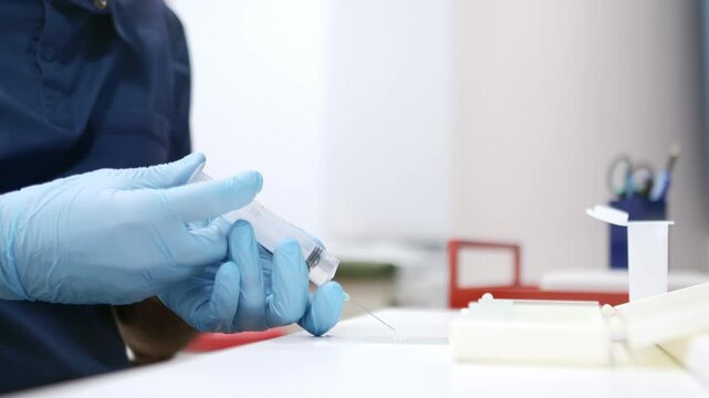 An oncologist performing a cancer biopsy during a patient's appointment. The doctor applies a sample from a syringe to a slide. Laboratory cancer diagnosis