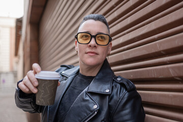 Woman wearing leather jacket and sunglasses holding coffee