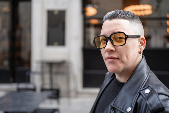 Woman with masculine style wearing yellow sunglasses and leather jacket