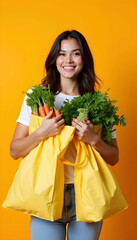 Smiling woman holding eco-friendly bags filled with fresh vegetables against a yellow background..