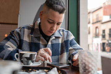 Woman using mobile phone while having coffee in cafe