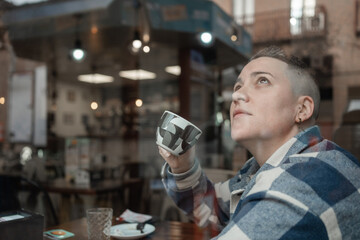 Woman enjoying a cup of coffee and looking up in a cafe