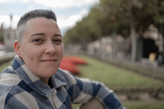 Short-haired woman smiling outdoors in urban park