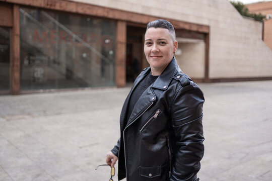 Confident lesbian woman smiling outdoors wearing leather jacket