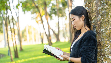 Obraz premium Happy girl reading a book in park, concept of Relaxation.