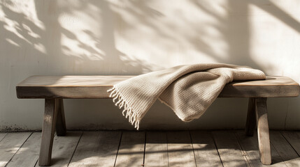 A single, folded blanket on a simple wooden bench, for comfort.
