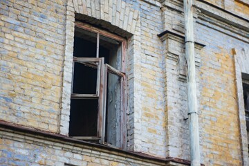 Close-up view of a dilapidated brick building with a broken window and peeling paint No texts present candid photograph documenting the condition