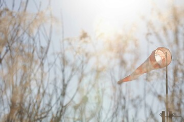Cinematic view of a windsock blowing against a clear blue sky in a field of tall grass.