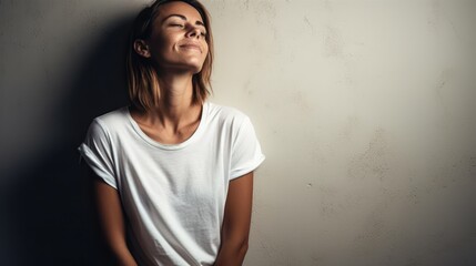 Obraz premium Portrait of a happy woman in white t-shirt leaning against grunge wall smiling casual beauty