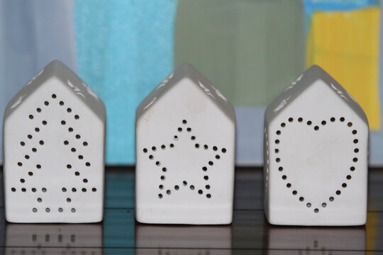 Three ceramic holiday light holders in shape of houses with drill holes for light to shine