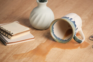 A drink was accidentally spilled on a desk with a laptop and glasses, creating a mess